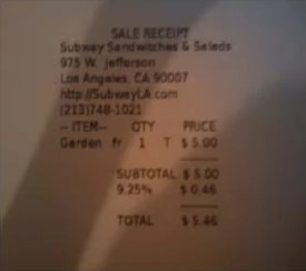 A thermal till receipt photographed at an angle in poor light, its print barely visible